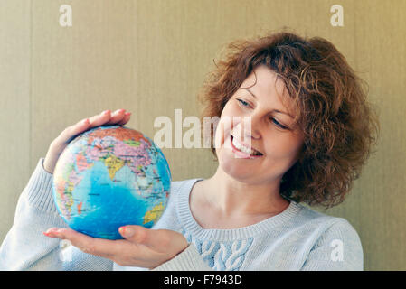 Frau mit Weltkugel in Händen denken über das Reisen Stockfoto