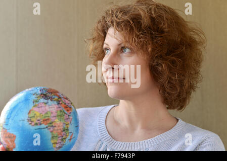 Frau mit Weltkugel in Händen denken über das Reisen Stockfoto