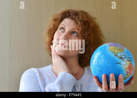 Frau mit Weltkugel in Händen denken über das Reisen Stockfoto