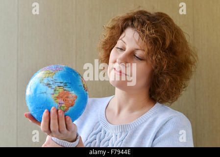 Frau mit Weltkugel in Händen denken über das Reisen Stockfoto