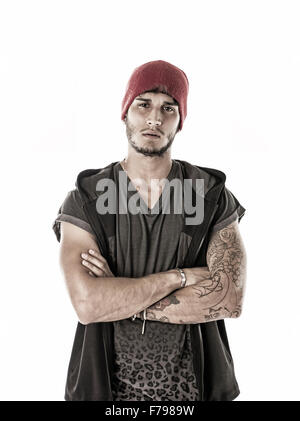 Hübscher harter junger Mann im dunklen Kapuzen T-shirt und rote Mütze, isoliert auf weißem Hintergrund, Blick in die Kamera mit Armen cros Stockfoto