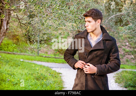 Hübscher muskulöser junger Mann Wandern in üppigen grünen Parklandschaft Blick auf einer Seite