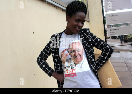 Kampala, Uganda. 27. November 2015. Eine Frau zieht gerne Souvenir T-shirt mit einem Willkommens-Nachricht für Papst Francis in der ugandischen Hauptstadt Kampala. Die Papst wird voraussichtlich Uganda am 27-29. November während einer Afrika-Reise besuchen, die Kenia und der Zentralafrikanischen Republik zu bedecken. Bildnachweis: Samson Opus/Alamy Live-Nachrichten Stockfoto