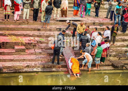 Hinduistische Leute besuchen einen religiösen Begräbniszeremonie einer toten Person am Ufer des Bagmati Fluss bei Pashupatinath Tempel-Komplex Stockfoto