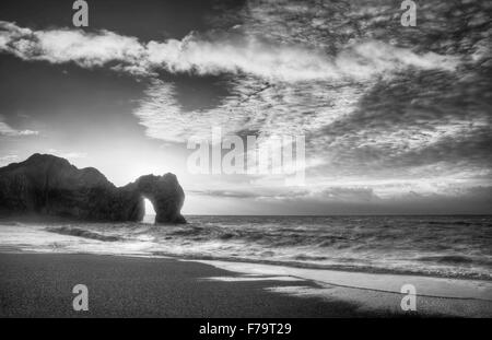 Winter-Sonnenaufgang hinter Durdle Door auf Jurassic Coast in schwarz / weiß Stockfoto