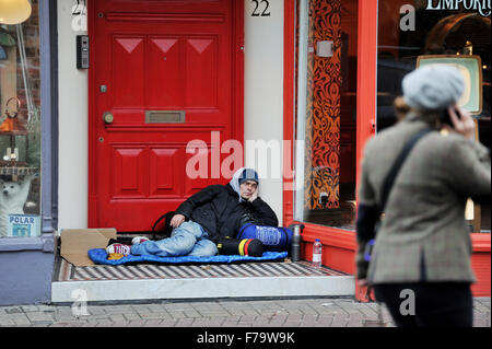 Ein Mann, der in der Ship Street Brighton rauh schläft, während die Leute vorbeikommen Stockfoto