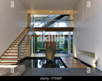 Offene Eingangshalle und das Treppenhaus mit Pool von Wasser und buddhistische Statue in Cove Way House, Sentosa, Singapur Stockfoto