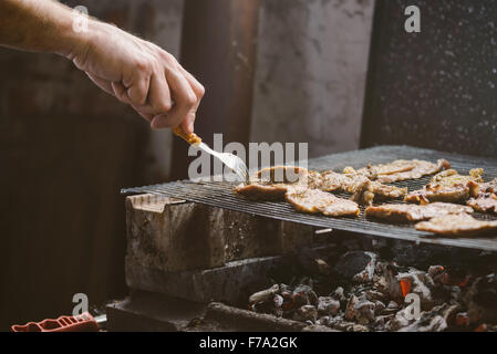 Schweinefleisch Grillen Mann hackt auf Grill, Retro getönt, selektiven Fokus mit geringen Schärfentiefe. Stockfoto