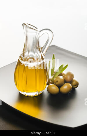 Glasflasche Premium natives Olivenöl und einige Oliven mit Blättern. Stockfoto