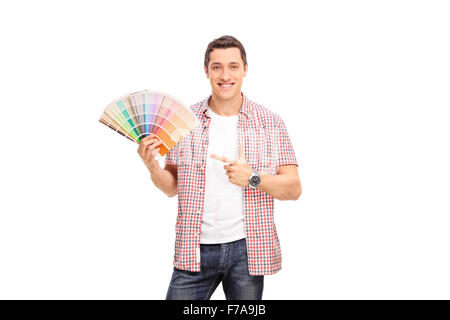 Fröhlichen jungen Mann ein Farbfeld in einer Hand halten und mit den anderen isoliert auf weißem Hintergrund zeigt Stockfoto