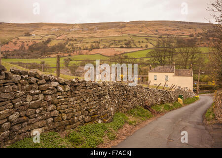 Malerische Aussicht auf eine kurvenreiche Straße führt von Reeth Dorf im Swaledale zeigt Fjälls, Stein, Mauerwerk und Häuser Stockfoto