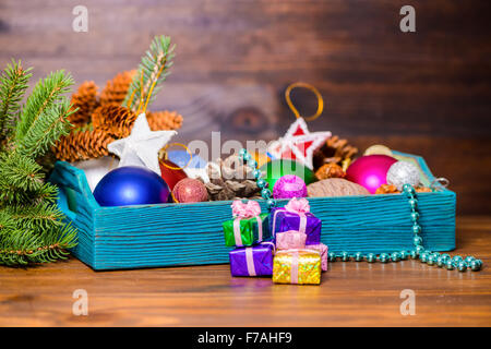 Zusammensetzung der Filiale Tanne, Vintage Holzbox mit Weihnachtsdekoration, Zapfen, Sterne, Kugeln und Geschenke auf hölzernen backgr Stockfoto