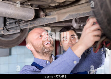 lächelnd zwei Männer in Overalls arbeiten am Auto reparieren Shop Closeup. Stockfoto