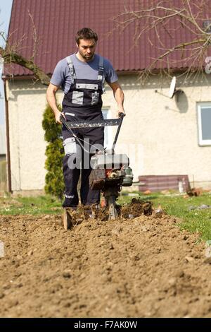 Mann ein Feld mit Hand motor Pflug Pflügen. Stockfoto