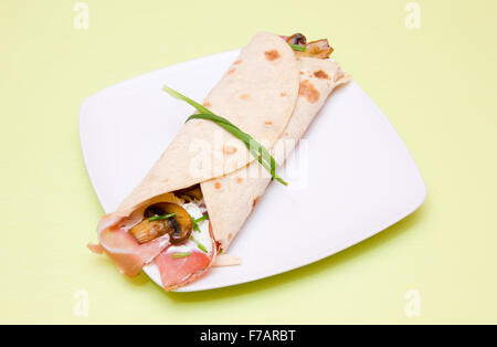 Fladenbrot mit Speck und Pilzen am grünen Tisch Stockfoto