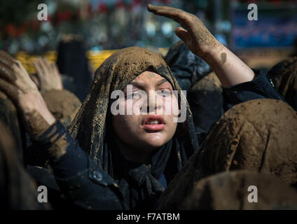 Iranische Schiiten junge Muslimin bedeckt im Schlamm, singen und sich überschlagender während Ashura, der Tag des Todes von Imam Hussein, Provinz Kurdistan, Bidjar, Iran Stockfoto