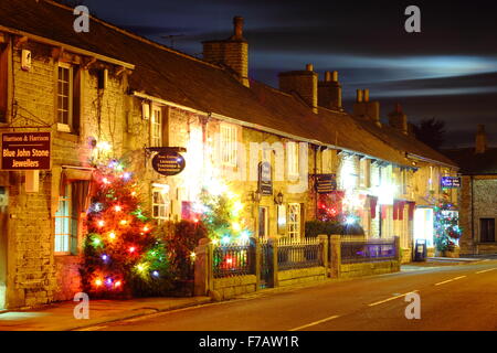 Beleuchtete Weihnachtsbäume säumen die Hauptstraße in Castleton; ein Dorf im Peak District, Derbyshire UK Stockfoto