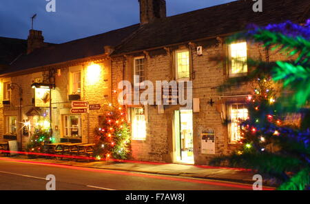 Dekorierte Weihnachtsbäume leuchten auf der Hauptstraße in Castleton; ein traditionelles Dorf im Peak District, Derbyshire, England Stockfoto