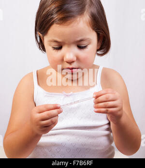 Kleines Mädchen auf der Suche zu einem klinischen Quecksilber-in-Glas-thermometer Stockfoto