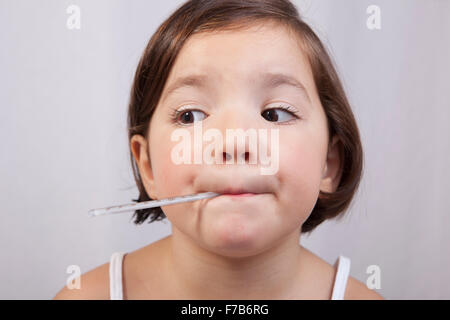 Kleines Mädchen mit einem klinischen Quecksilber-in-Glas-Thermometer im Mund Stockfoto