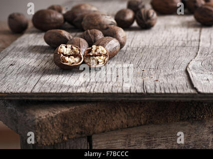 ganze und gehackte Pekannüsse auf alten Holztisch. Stockfoto