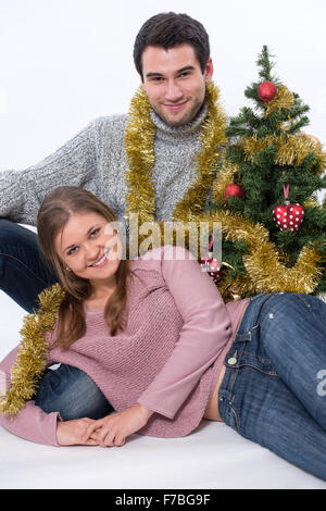 Junges Paar, Mann und Frau, Sitzen durch Weihnachtsbaum Stockfoto