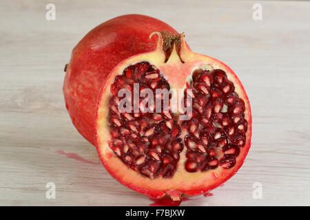 Granatapfel in Scheiben geschnitten in eine halbe Om ein Holzbrett Stockfoto