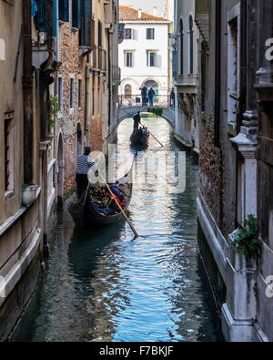 Venedig, Italien. Zwei Gondolieri Steuern Gondeln an einem schmalen venezianischen Kanal unter einer Brücke Stockfoto