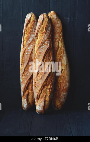 Frische knusprige Baguette auf dunklem Holz Stockfoto