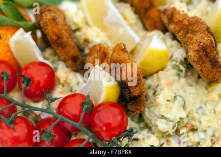 Kartoffelsalat mit Wiener Schnitzel und einem Stück Zitrone, Schale Kirschtomaten traditionelle tschechische für Weihnachtsessen Stockfoto