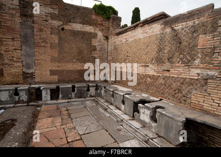 Die großen Ausgrabungen der alten Hafenstadt des antiken Rom Ostia Antica zeigt gut erhaltene Gebäude wie diese Toiletten. Stockfoto