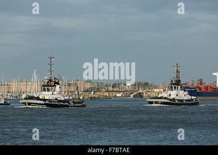 Passenden Schlepper aus Portsmouth Harbour. Weiße und schwarze Arbeitsboote, die Vorbereitung auf die Ankunft eines Containerschiffes Stockfoto