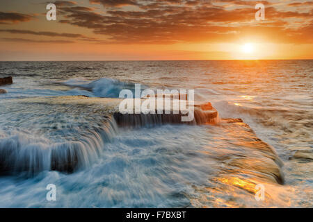 Pazifischen Ozean malerischen bunten Sonnenaufgang über dem Horizont in der Nähe von Maroubra Beach in Sydney mit fallenden Sufring Wasser von Küstenfelsen Stockfoto