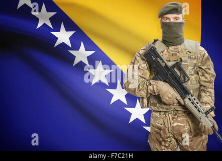 Soldat mit Maschinengewehr mit Nationalflagge auf Hintergrund - Bosnien und Herzegowina Stockfoto