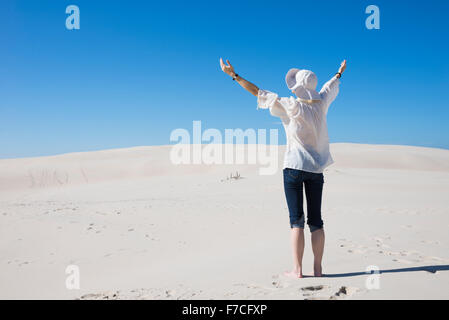 Frau hob ihre Hände in die Luft auf Sanddüne steht Stockfoto