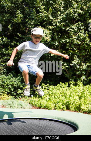 Kind mit Brille springen auf einem Trampolin in einem park Stockfoto