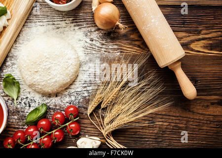 Pizzateig mit Zutaten auf Holz Stockfoto