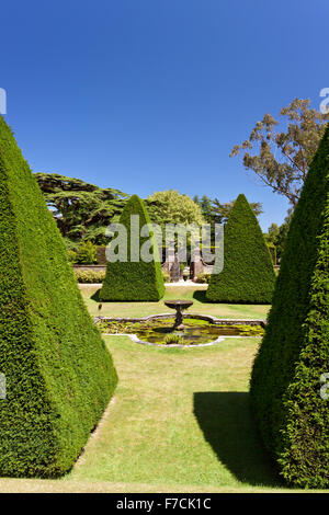 Beeindruckende abgeschnittene Eibe Baum Formschnitt Pyramiden in der versunkene Garten des großen Hofs in Athelhampton House, Dorset, England, UK Stockfoto