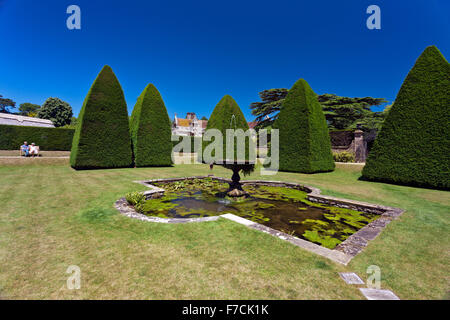 Beeindruckende abgeschnittene Eibe Baum Formschnitt Pyramiden in der versunkene Garten des großen Hofs in Athelhampton House, Dorset, England, UK Stockfoto