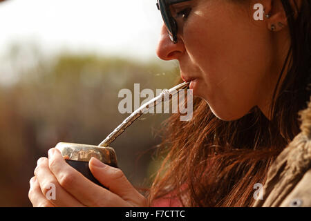 junge Frau trinken Mate aus einem Mate-Becher durch ein Mate-Rohr. Stockfoto