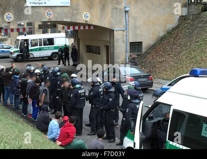 Berlin, Deutschland. 29. November 2015. Polizisten stehen neben Flüchtlingen, die vorübergehend in Gewahrsam auf den ehemaligen Flughafen Tempelhof in Berlin, Deutschland, 29. November 2015 ergriffen wurden. Flüchtlinge mit Messer und Stangen miteinander in eine Massenschlägerei in einem Flüchtlingsheim auf dem Gelände des ehemaligen Flughafens angegriffen. Foto: PAUL ZINKEN/Dpa (Achtung Redaktion: die Gesichter von mehreren Individuen wurden verpixelt aus rechtlichen Gründen über persönliche Rechte.) / Dpa/Alamy Live News Stockfoto