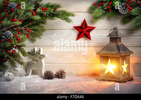 Weihnachten Hintergrund der Szene mit einer Laterne, Tannenzweigen, roter Stern, Rentier und Schnee vor der helle Holzplatte mit cand Stockfoto
