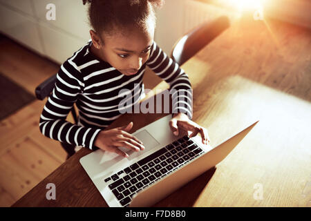 Erhöhte Ansicht von oben von einem netten jungen afrikanischen Mädchen Surfen im Web mit einem Laptop-Computer in einer pädagogischen oder Freizeit c
