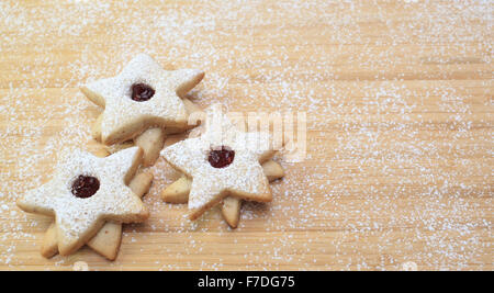 Drei sternförmige Cookies auf einem Holztisch in Mehl bedeckt. Stockfoto