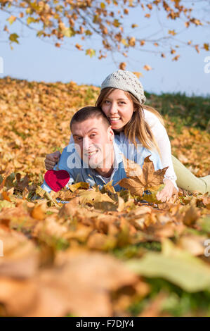 Glückliches Liebespaar auf den abgefallenen Blättern liegend Stockfoto