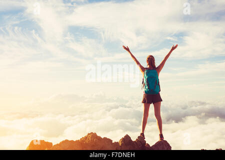 Glückliche junge Frau Wanderer mit offenen Armen angehoben bei Sonnenuntergang auf Berggipfel Stockfoto