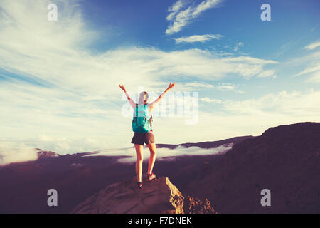 Junge Frau glücklich Wanderer mit Rucksack stehend auf Berggipfel mit offenen Armen Stockfoto
