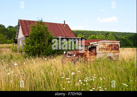 Eine rostige alte LKW und Bauernhaus in einem verwilderten Wiese Stockfoto