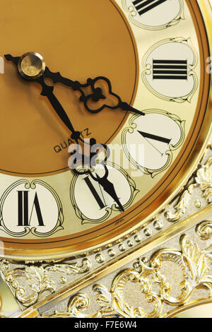 eine alte goldene Uhr mit römischen Ziffern auf weißem Hintergrund Stockfoto