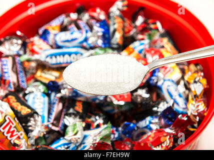 Einen Löffel Zucker mit einer Auswahl an Pralinen aus der Dose von feiern. Stockfoto